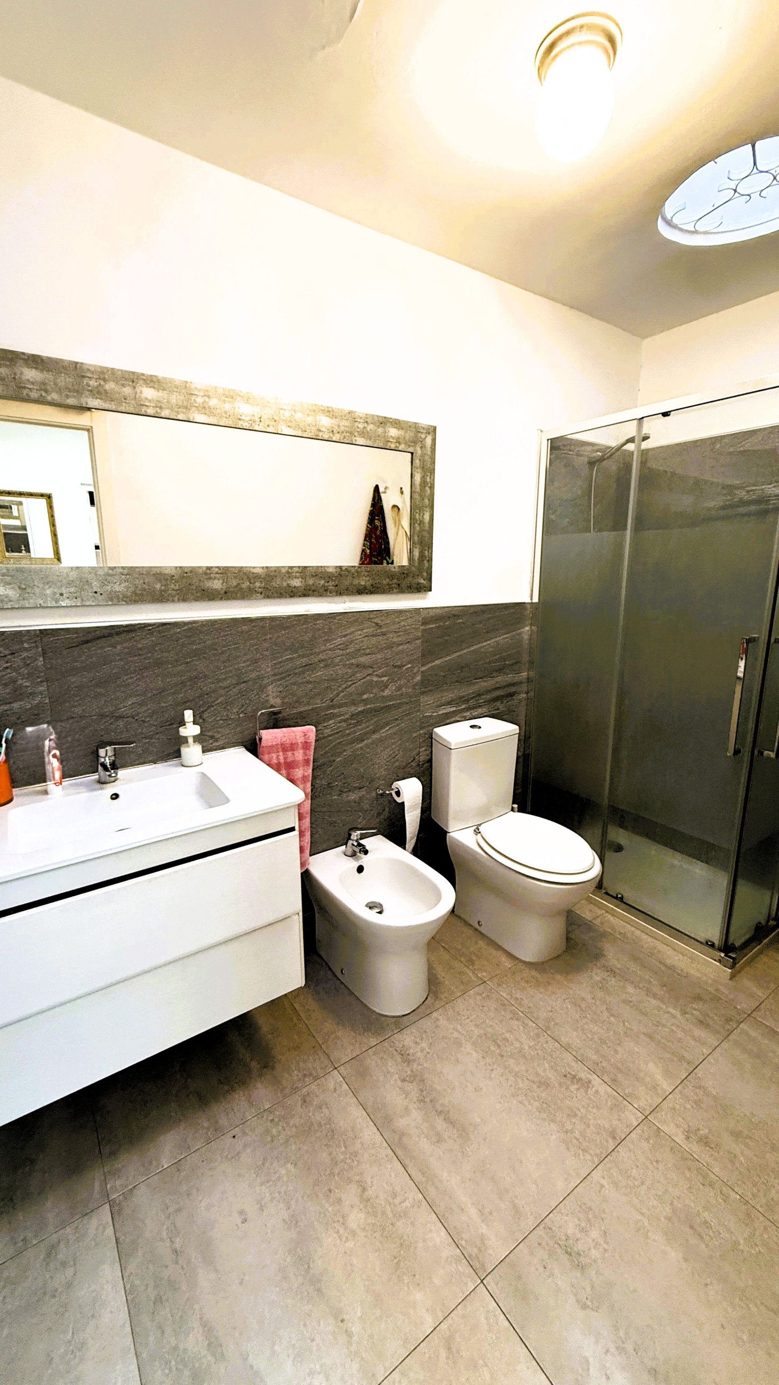 Modernes Badezimmer mit separatem WC, großflächigem Spiegel und ebenerdiger Duschkabine