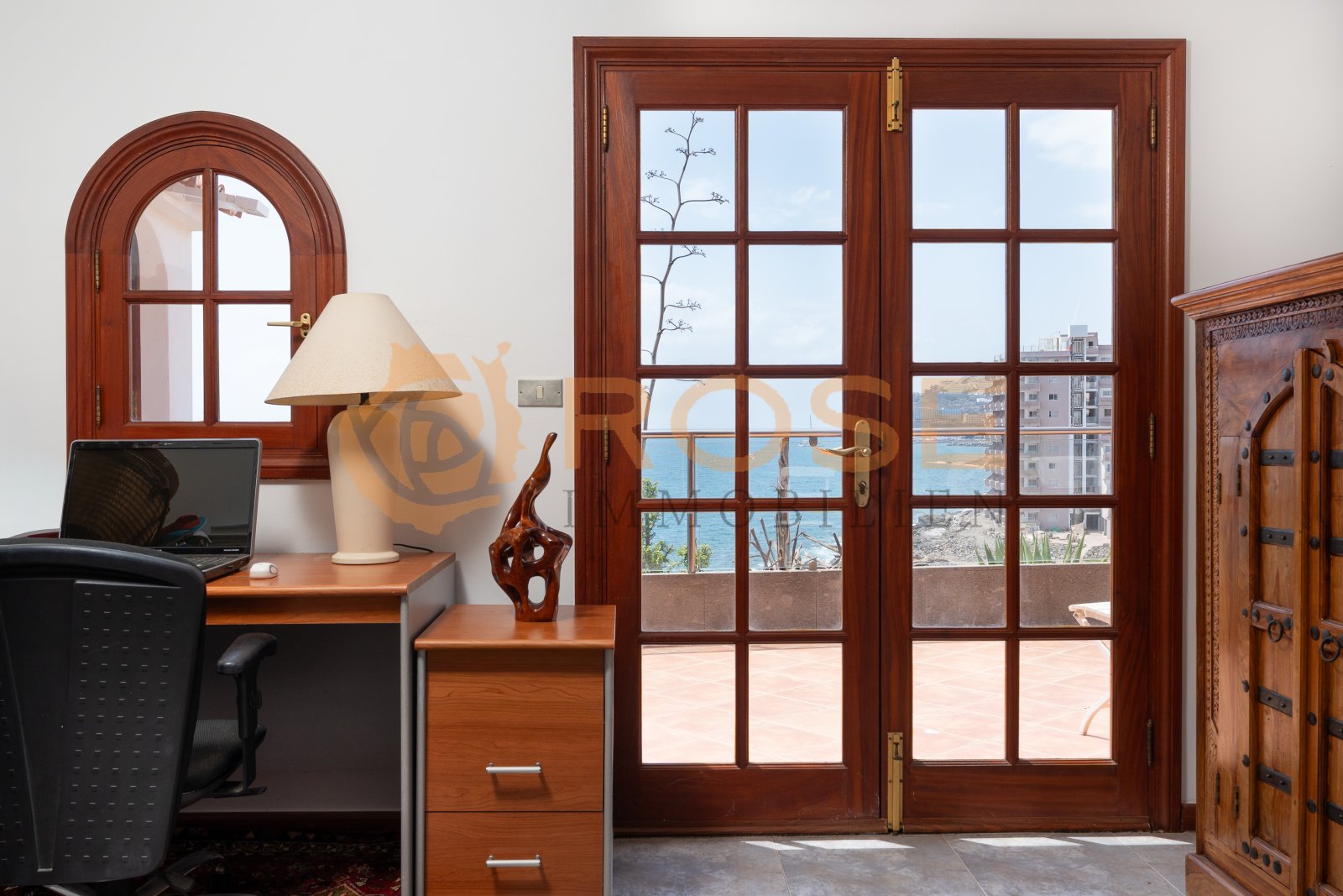 Elegantes Arbeitszimmer mit Rundbogenfenster und direktem Meerblick-Zugang durch Glasschiebetüren