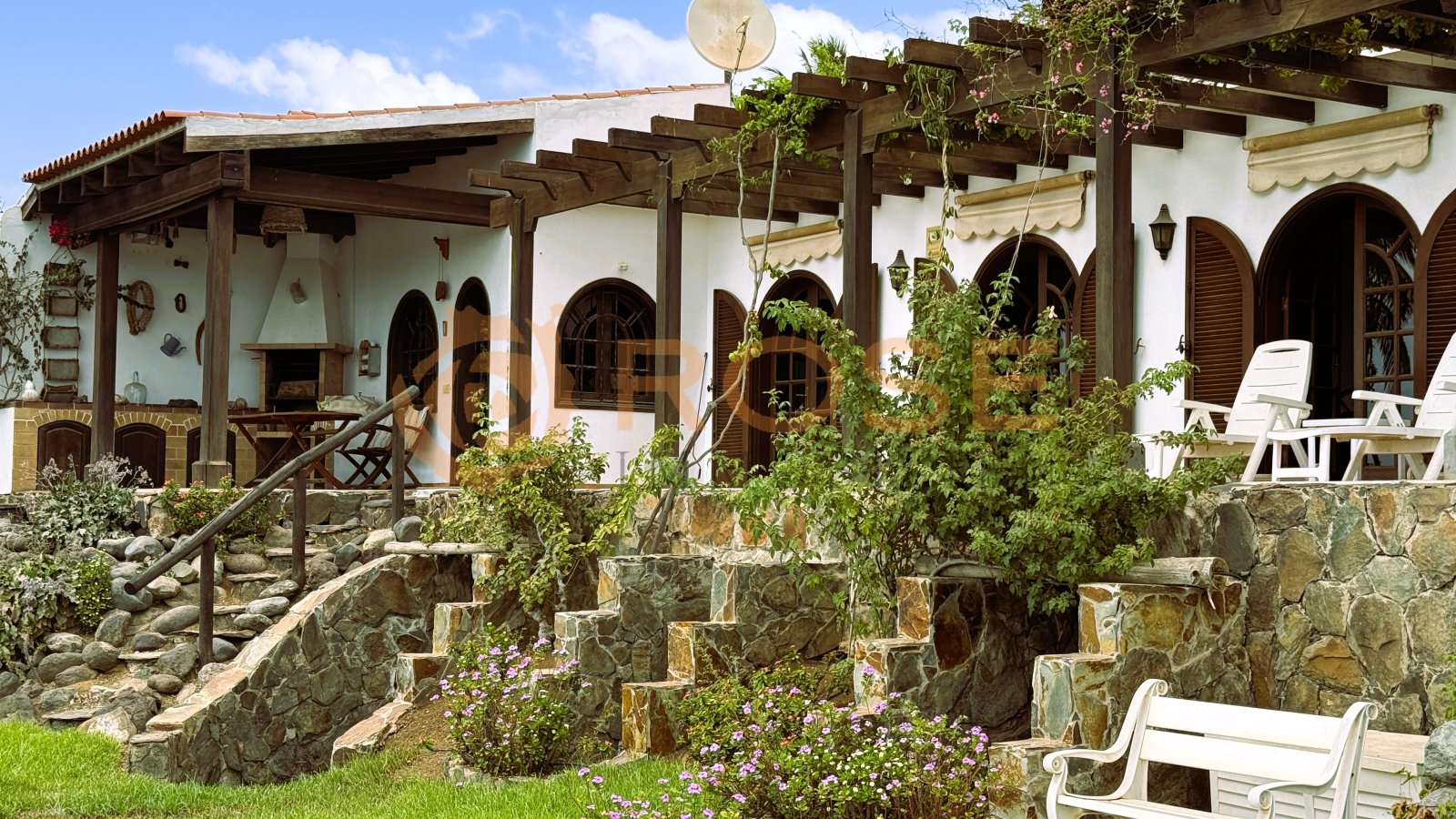 Terrassenbereich mit rustikalen Steinmauern und eleganter Pergola-Überdachung