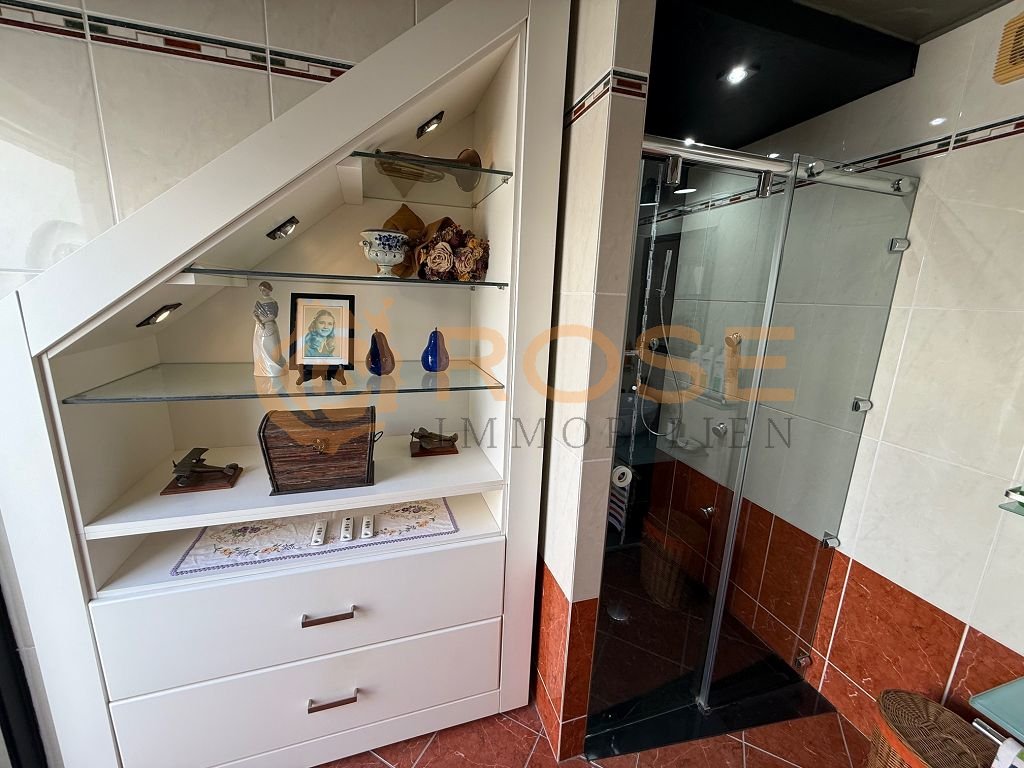 Bathroom with walk-in shower and smart storage integration under the sloped ceiling