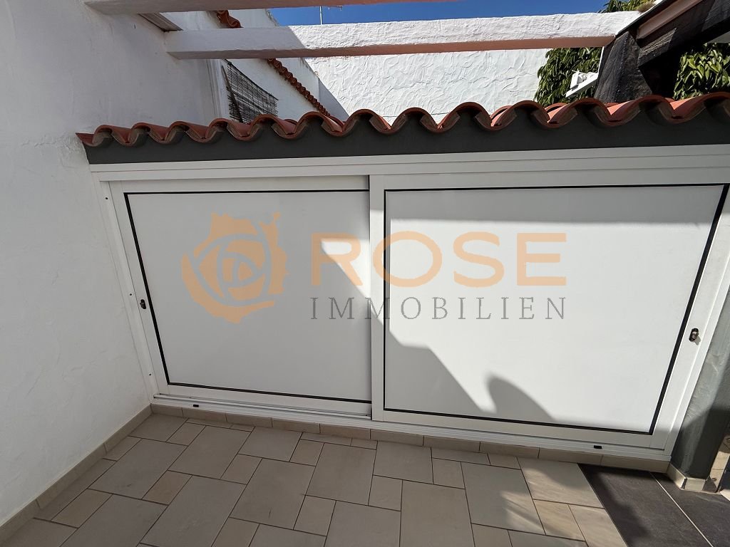 Terrace area with motorized roller shutter system and weather-protective pergola construction