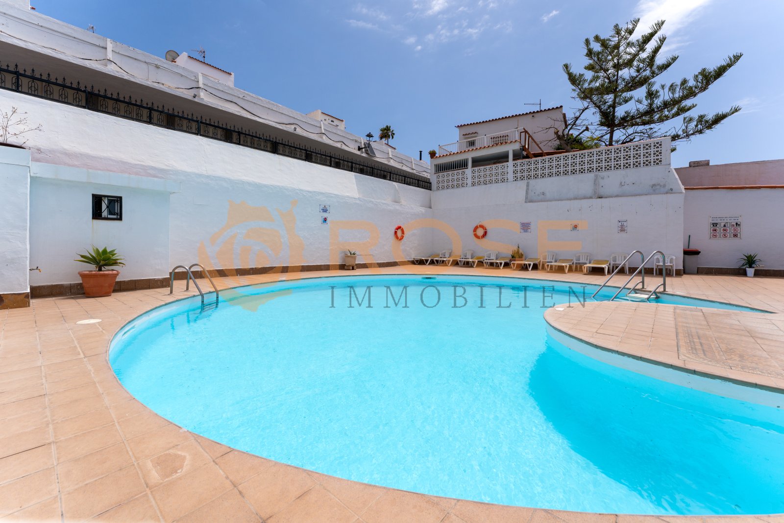 Refreshing communal pool with a spacious sun terrace and modern loungers