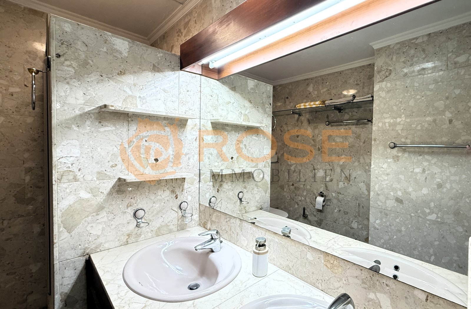Elegant bathroom with natural stone cladding and frameless shower enclosure – timeless elegance in the wet area