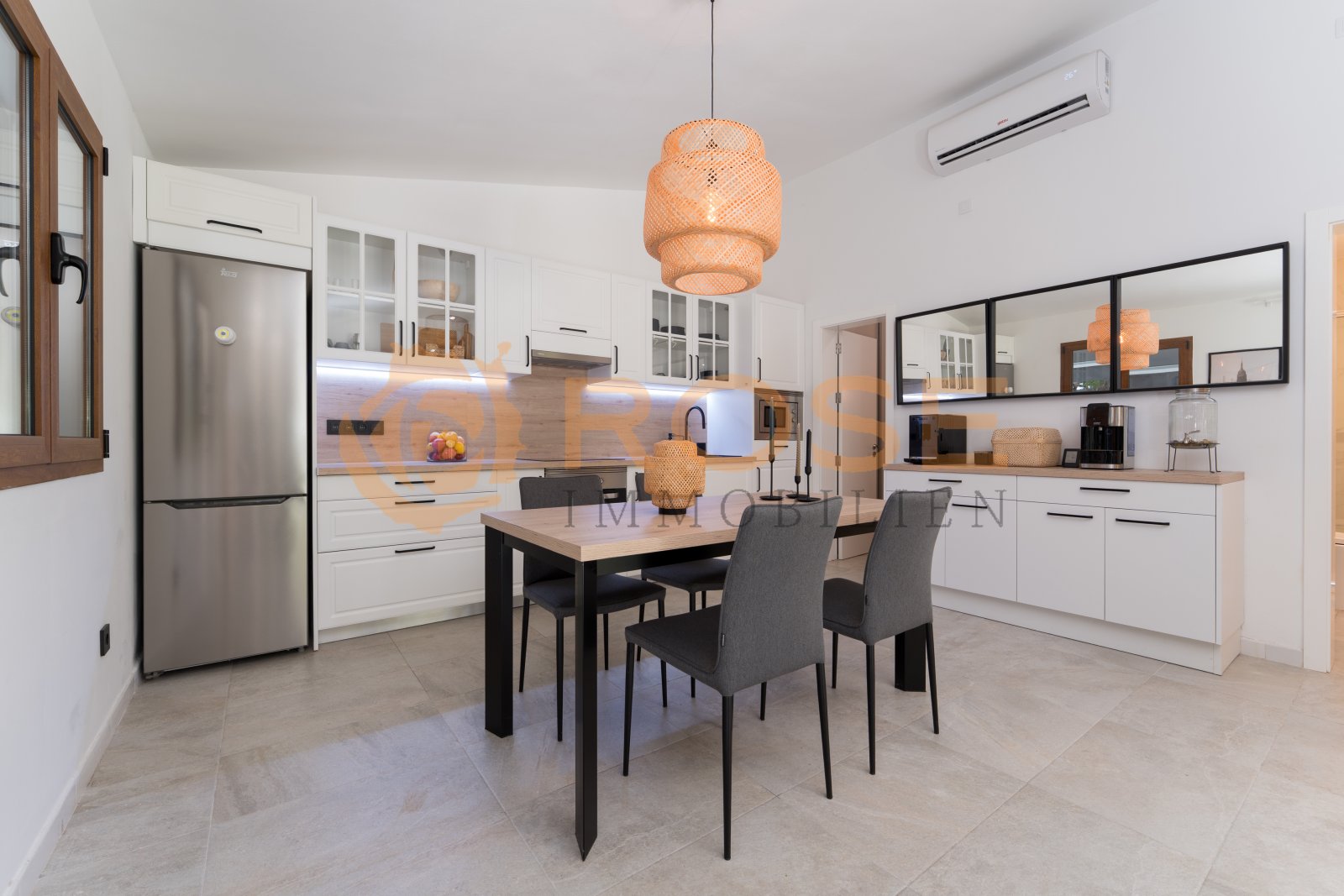 Modern kitchen and dining area with integrated air conditioning and mirrored backsplash Modern kitchen and dining area with integrated air conditioning and mirrored backsplash