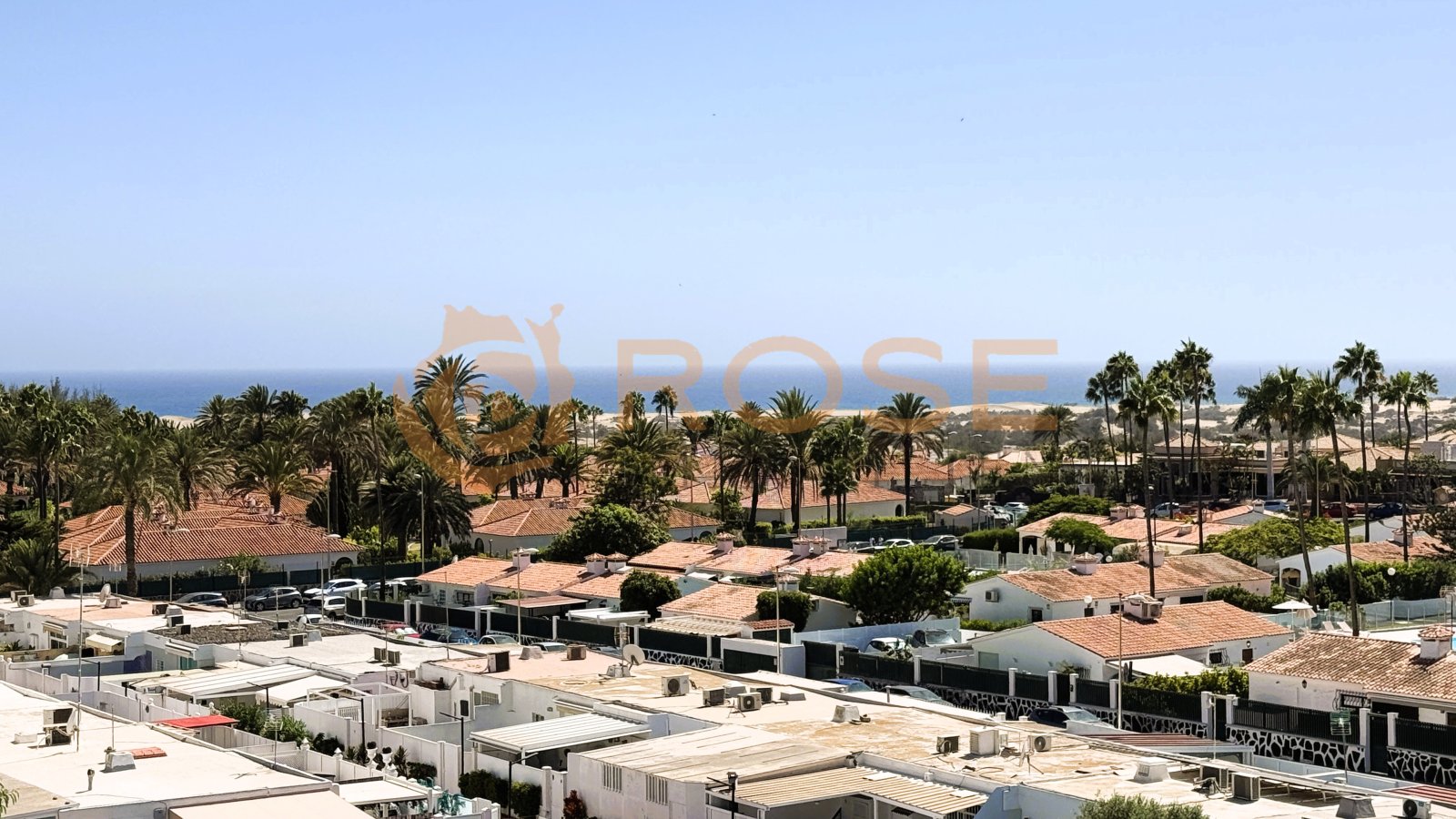 Aerial view: residential complex with communal pool, sea view, and Mediterranean surroundings