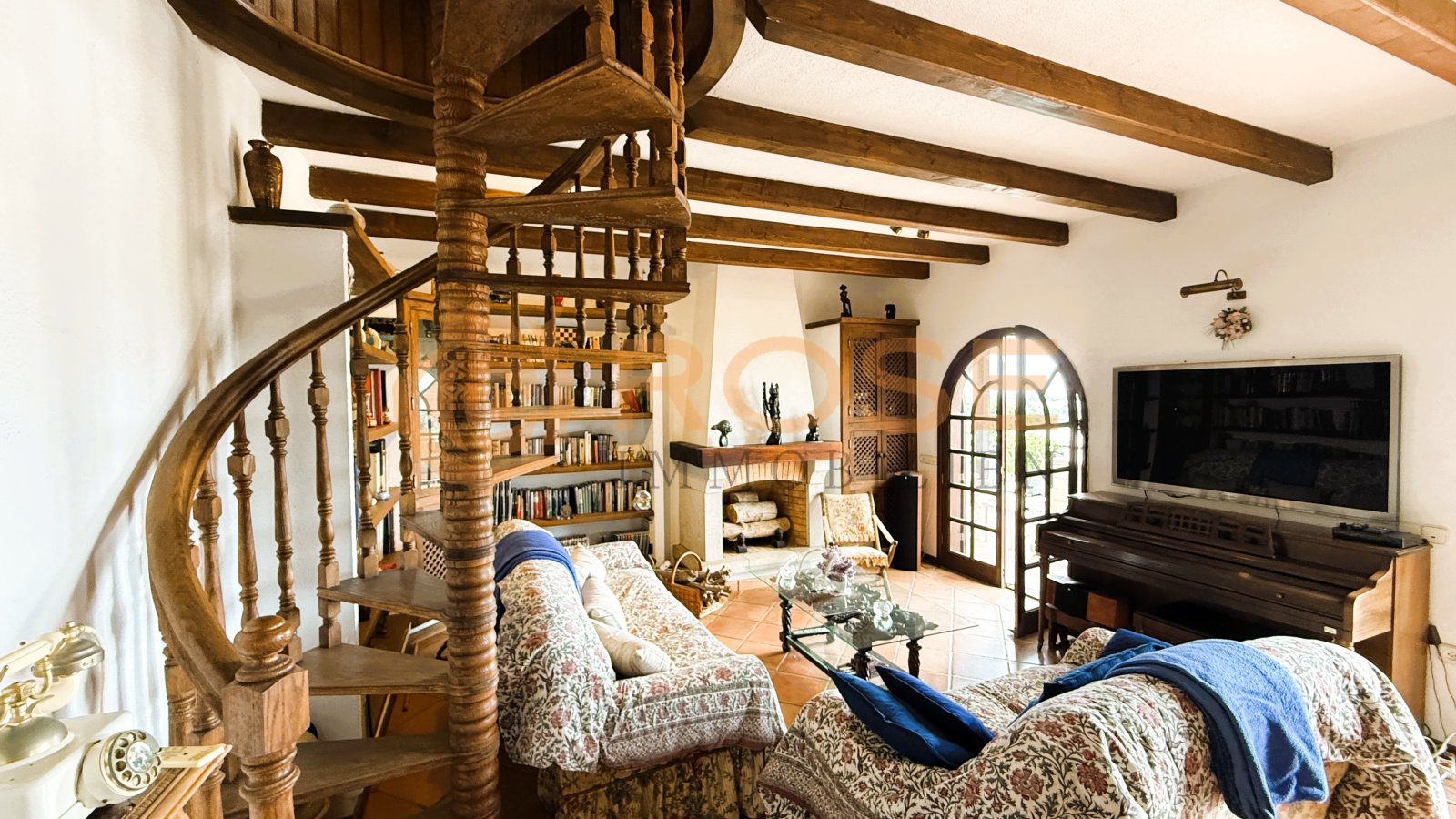 Living area with distinctive wooden beams and an elegant spiral staircase to the upper floor