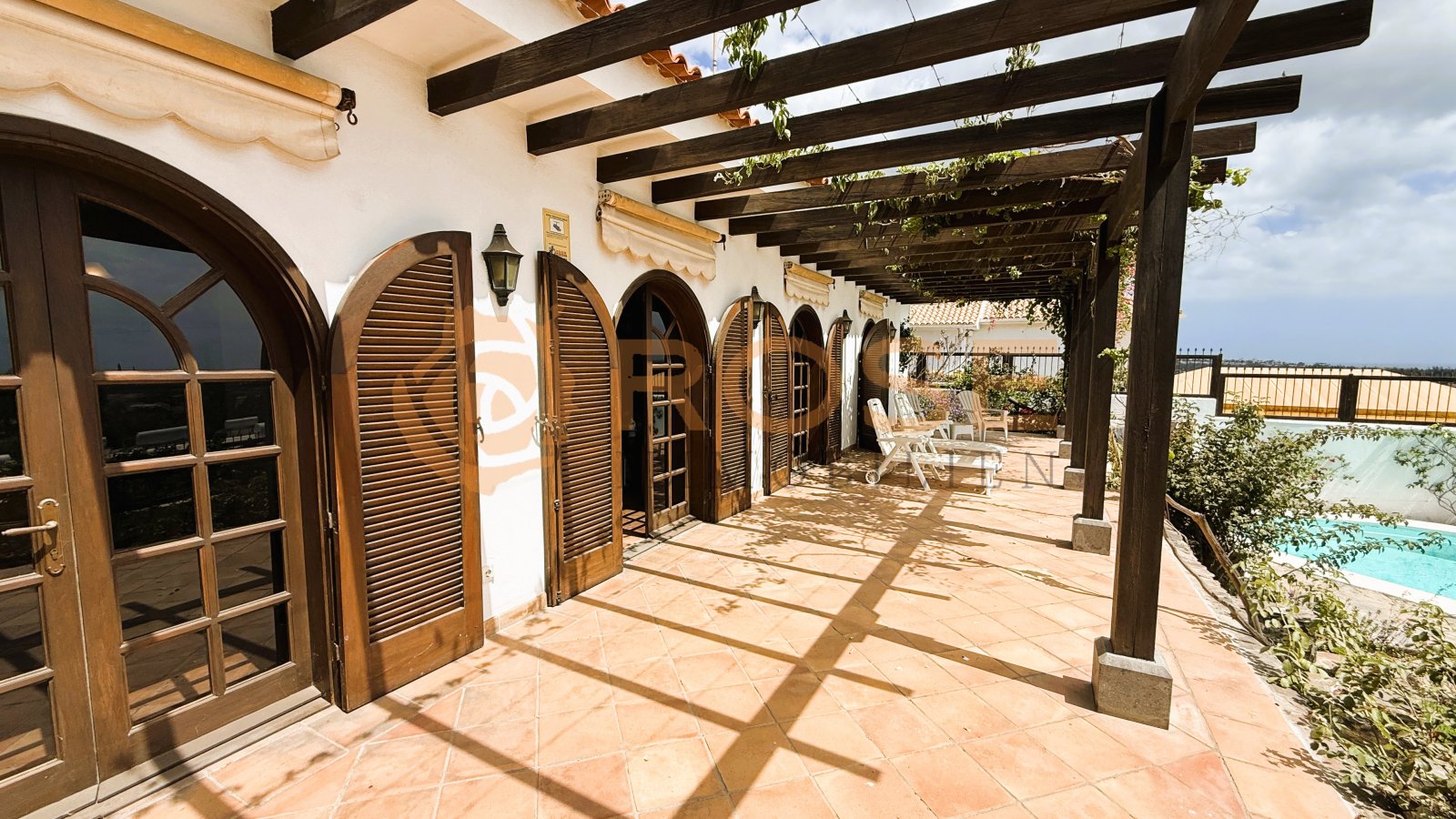 Covered arcade terrace with round-arch openings and direct pool access