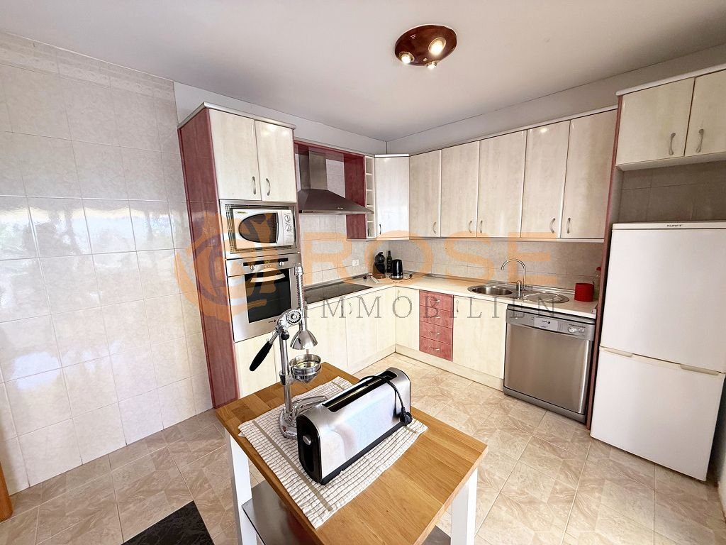 Cocina moderna en forma de L con equipamiento de electrodomésticos de alta calidad