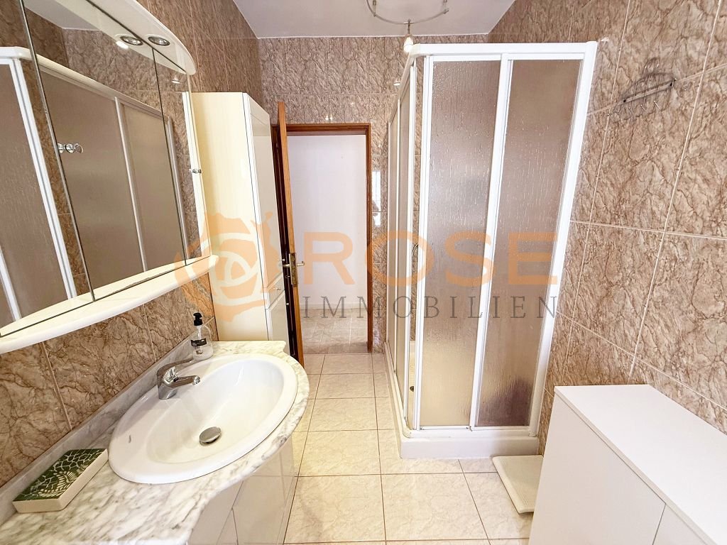 Baño elegante con ducha separada y espejo de gran tamaño