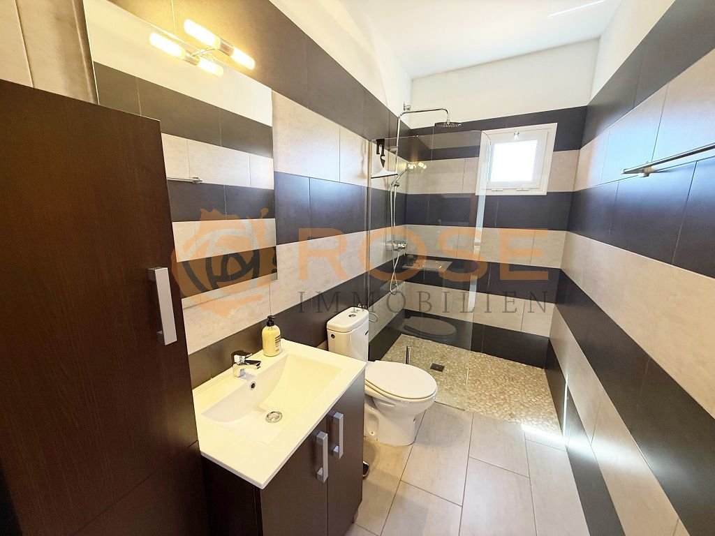 Baño moderno con ducha a nivel del suelo y zona de lavabo práctica