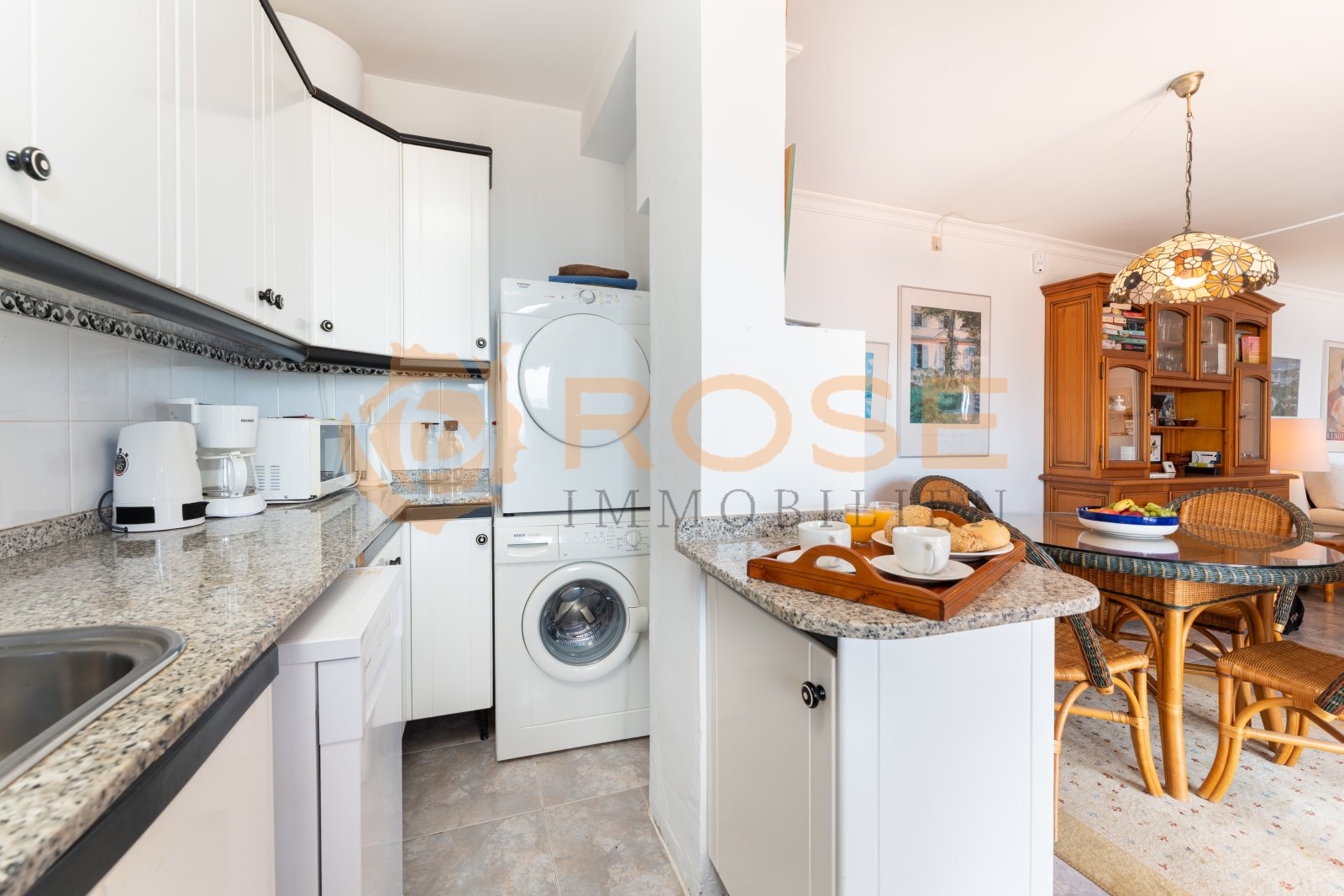 Cocina práctica con zona de lavandería integrada y conexión fluida con el comedor