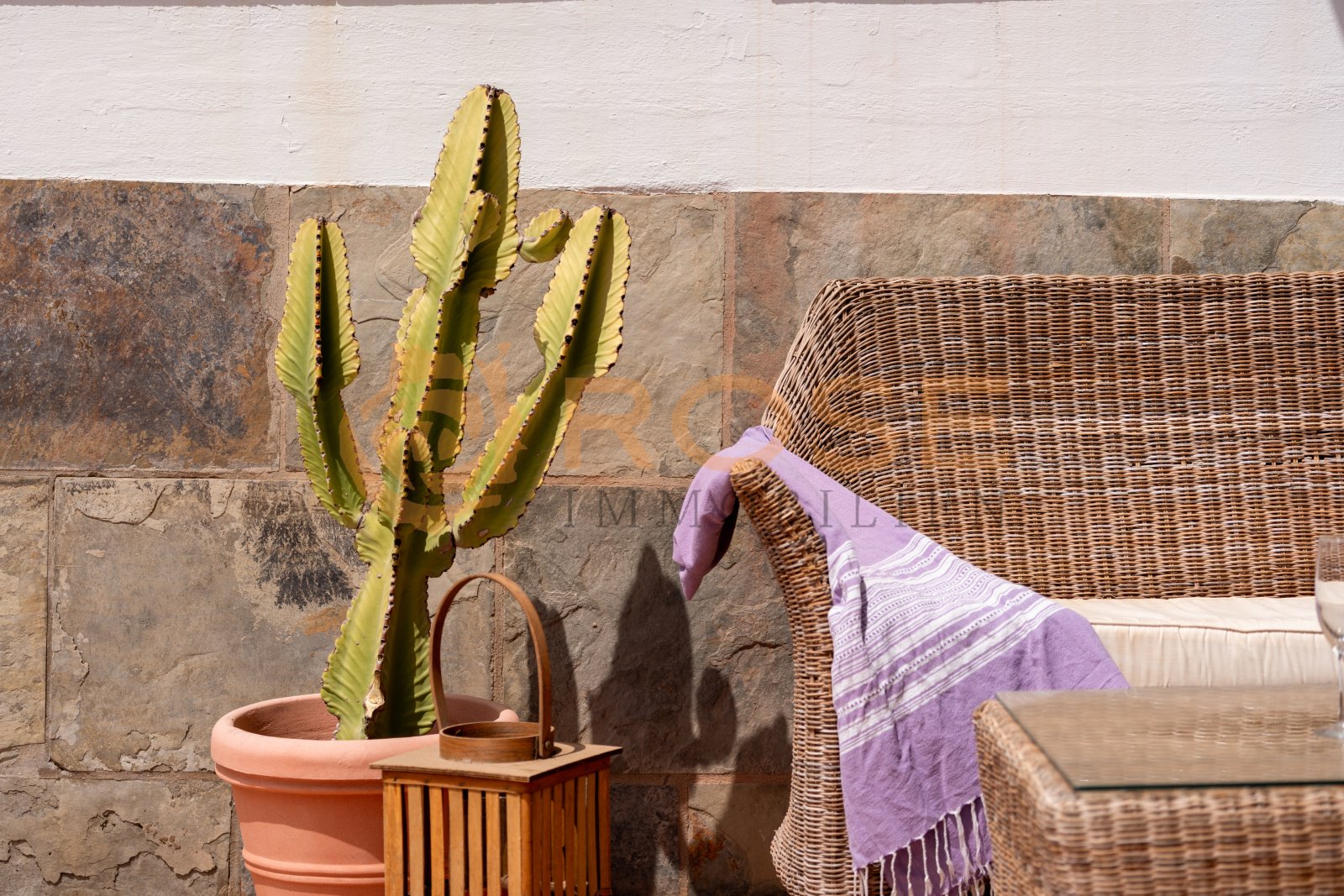 Terraza cubierta con pared de piedra natural y protección contra el viento integrada – su zona de bienestar protegida