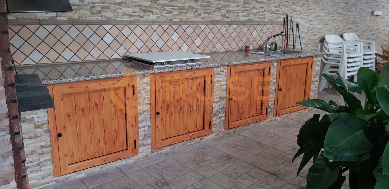 Cocina exterior con armarios de madera maciza y encimera de gran superficie