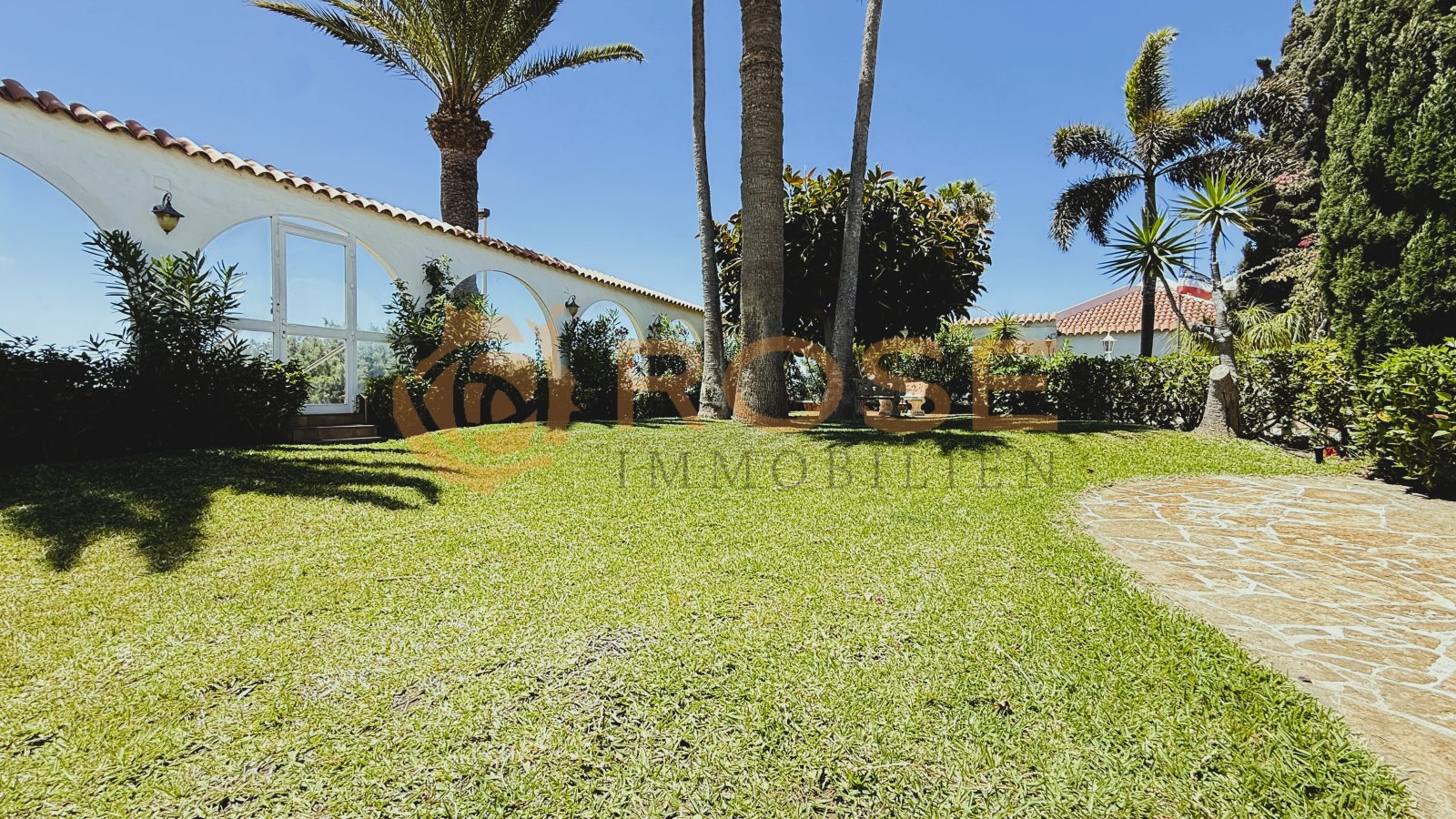 Patio interior bañado por el sol con arcos y pavimento de piedra natural – punto de encuentro ideal para el disfrute al aire libre