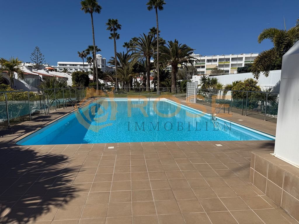 Piscine communautaire avec une grande surface de détente et une clôture sécurisée